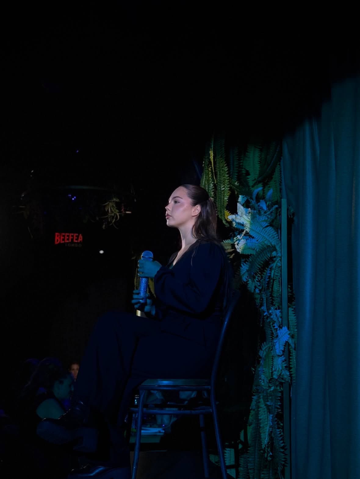 Rocío cantando sentada en un taburete en un directo