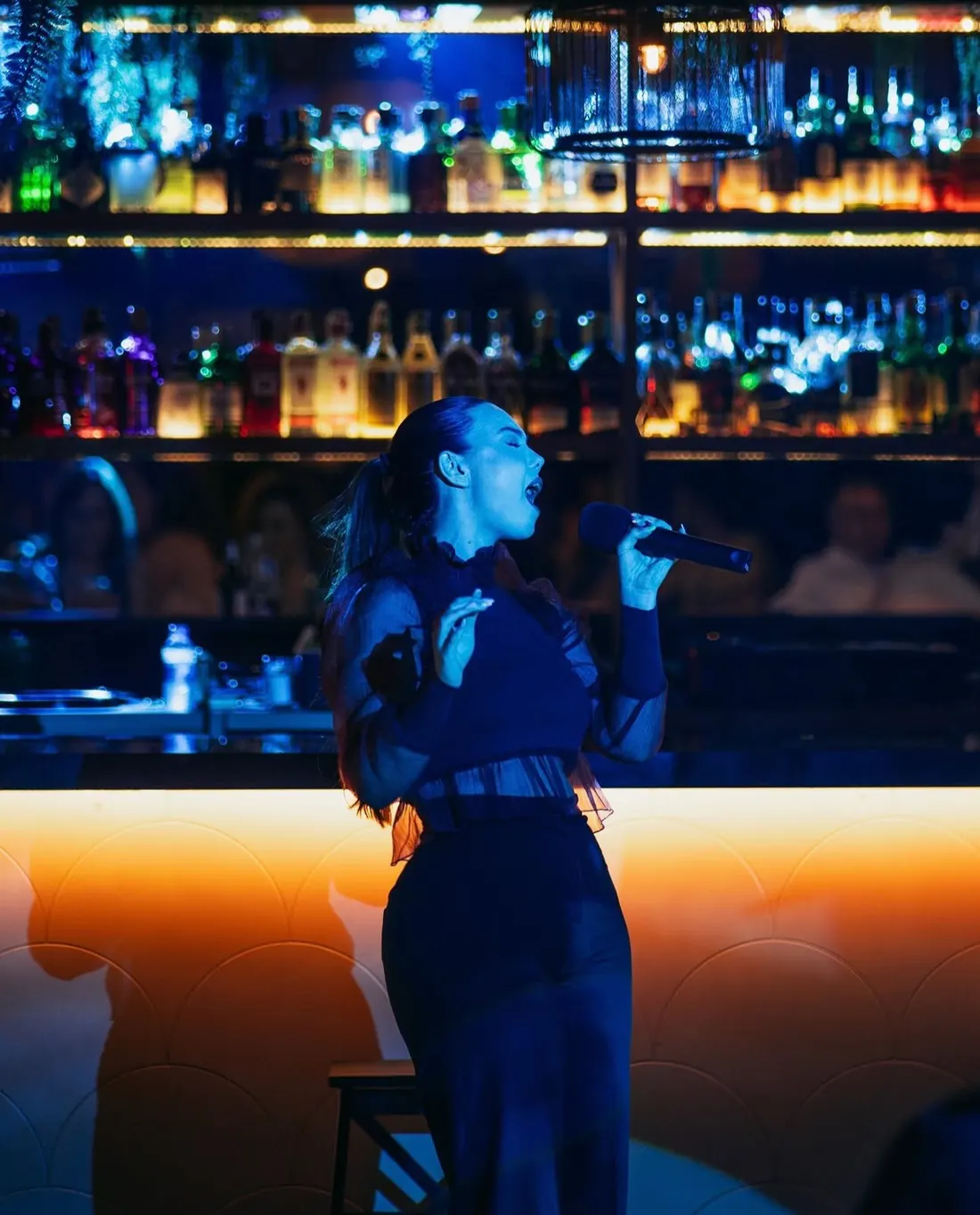 Rocío cantando de pie ante la barra en un directo