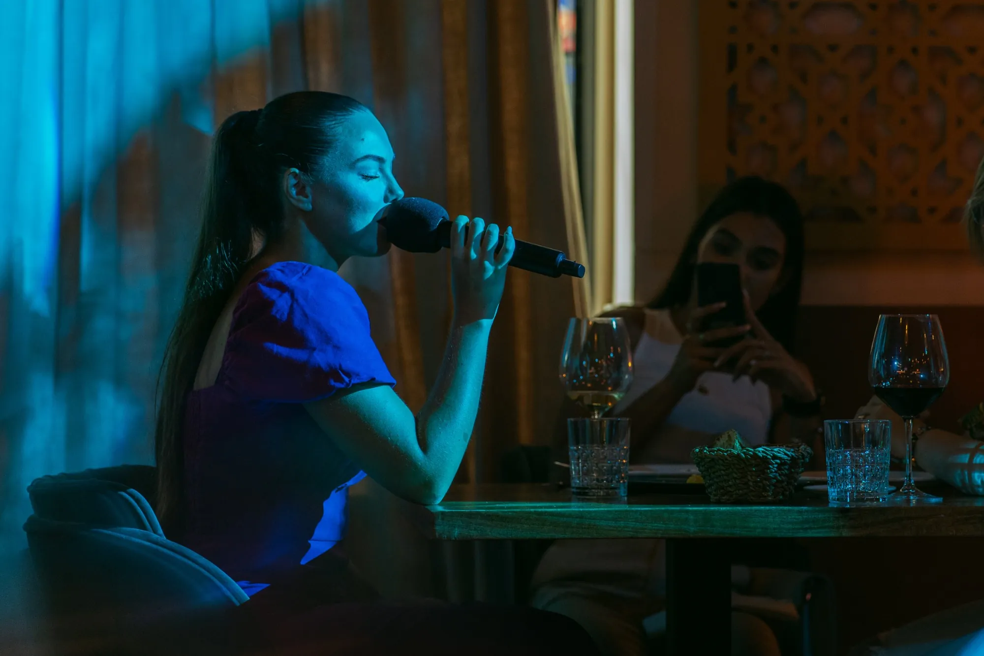 Rocío cantando sentada a una mesa mientras una invitada la graba